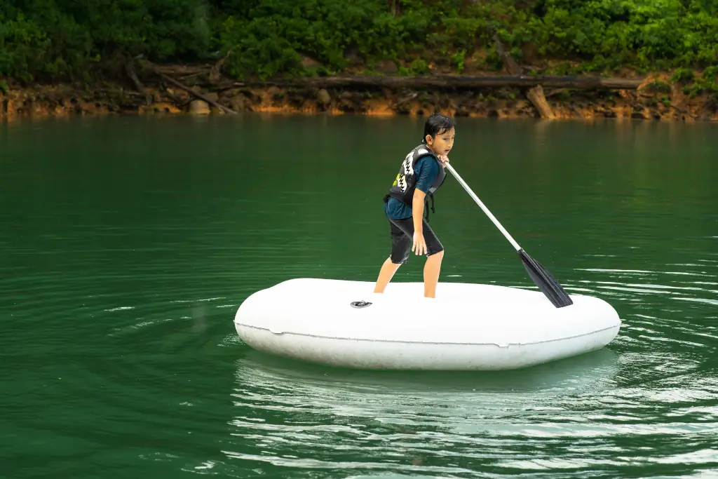 Kleiner Junge paddelt mit dem Schlauchboot