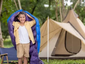 Junge beim Camping mit Schlafsack und Zelt