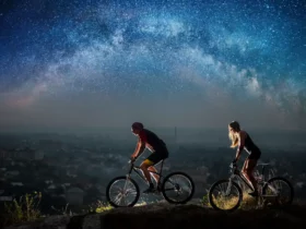 Sportliches Paar fährt nachts mit Beleuchtung Fahrrad unter Sternenhimmel